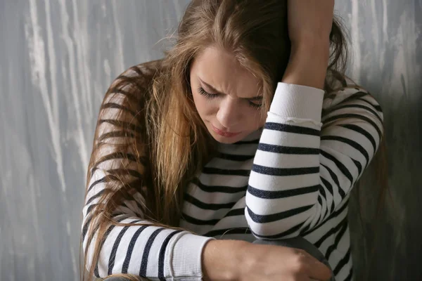 Lonely depressed woman near grey wall