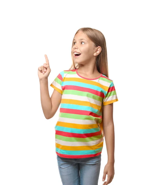 Маленькая девочка в футболке указывает на что-то на белом фоне — стоковое фото