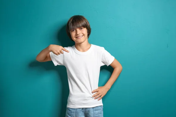 Little boy pointing at his t-shirt  on color background — Stock Photo, Image
