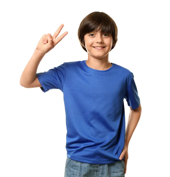 Garotinho sorridente em camiseta mostrando gesto de Vitória no fundo branco — Fotografia de Stock