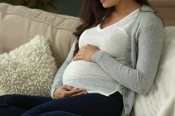 Красивая беременная женщина отдыхает дома на диване — стоковое фото