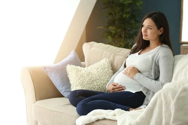 Красива вагітна жінка відпочиває на дивані вдома — стокове фото