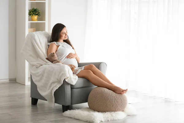 Hermosa mujer embarazada sentada en sillón en casa —  Fotos de Stock