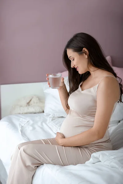 Beautiful pregnant woman drinking water in bedroom — Stock Photo, Image