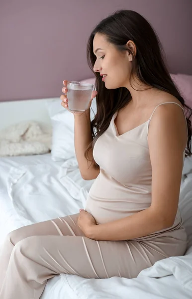 Beautiful pregnant woman drinking water in bedroom — Stock Photo, Image