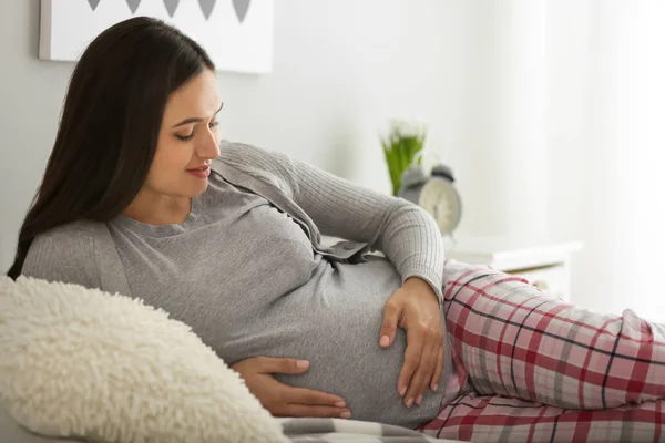 Schöne schwangere Frau ruht sich im Schlafzimmer aus — Stockfoto