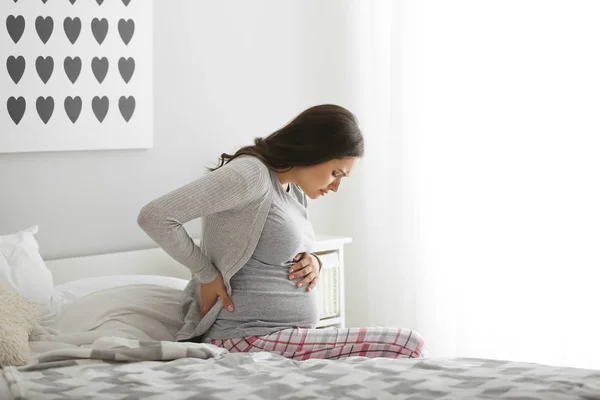 Mujer embarazada que sufre de dolor en el dormitorio —  Fotos de Stock