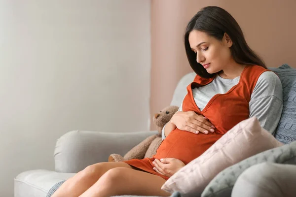 Красива вагітна жінка сидить на дивані вдома — стокове фото