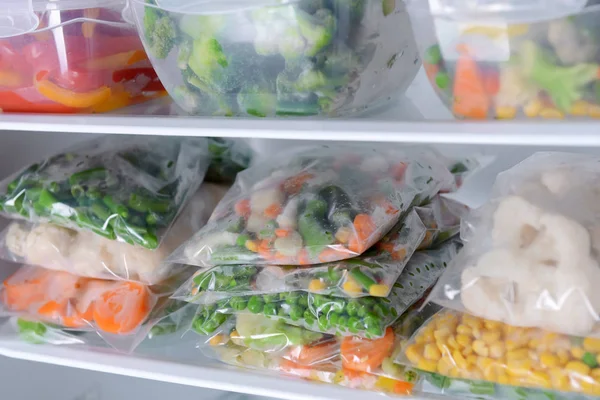 Plastic bags and containers with frozen vegetables in refrigerator — Stock Photo, Image