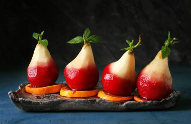 Plaka üzerinde portakal dilimleri ile kırmızı şarap lezzetli haşlanmış armut