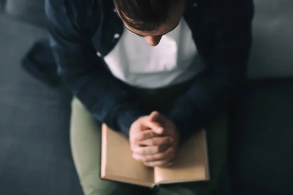 Religious young man with Bible praying at home — Stock Photo, Image