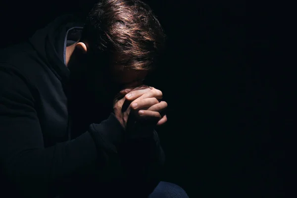 Религиозный юноша молится Богу на черном фоне — стоковое фото