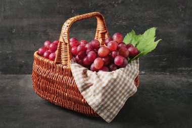 Hasır sepet gri arka plan üzerinde taze kırmızı üzüm ile