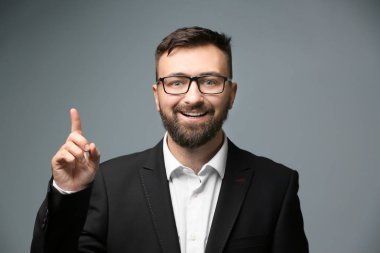 Işık arka plan üzerinde yükseltilmiş işaret parmağı ile mutlu işadamı