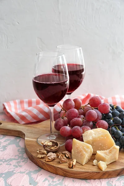 Vasos de vino tinto con queso y uvas maduras en la mesa — Foto de Stock