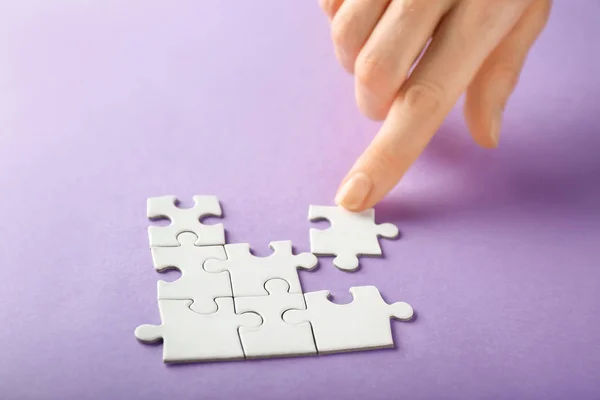 Hand of woman doing puzzle on color background, closeup — Stock Photo, Image