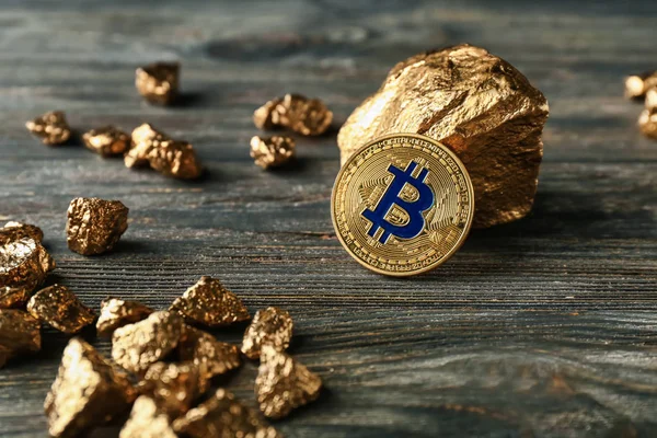 Gold nuggets and bitcoin on dark wooden background — Stock Photo, Image