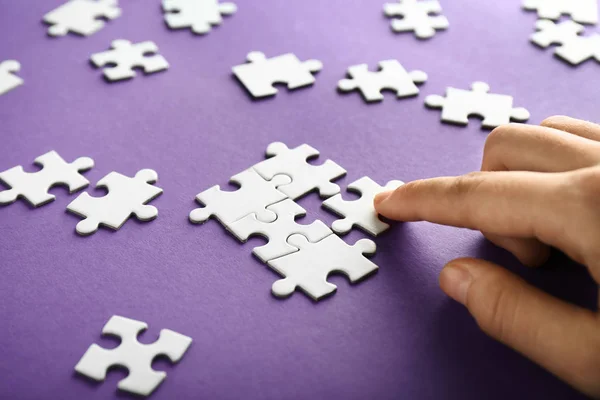 Mano della donna che fa puzzle su sfondo di colore, primo piano — Foto Stock