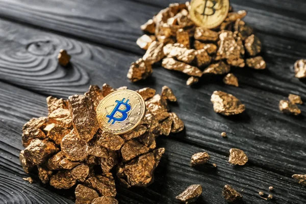 Pepitas de oro y bitcoins sobre fondo de madera oscura — Foto de Stock