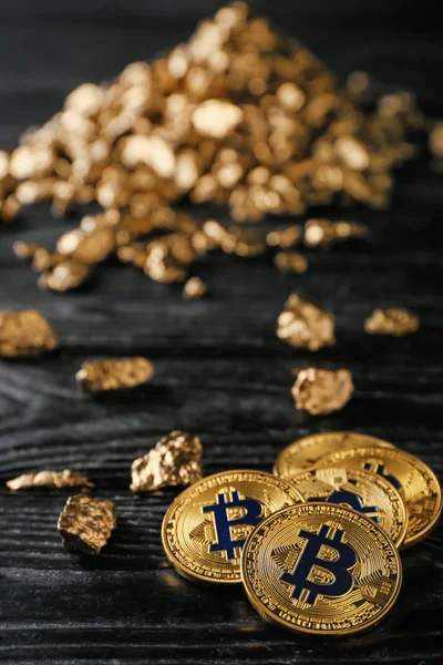 Bitcoins y pepitas de oro sobre fondo de madera oscura — Foto de Stock