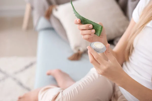 Schöne junge Frau verwendet Creme mit Aloe Vera-Extrakt zu Hause — Stockfoto