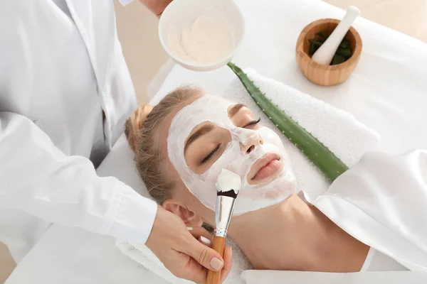 Kosmetolog tillämpa mask med aloe vera extrakt ansiktet av ung kvinna i skönhetssalong — Stockfoto