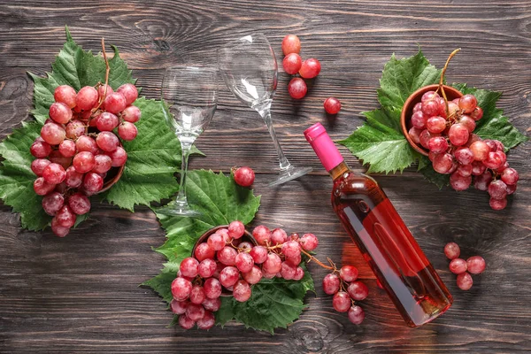 Bottiglia di vino rosso, bicchieri e uva matura sul tavolo di legno — Foto Stock