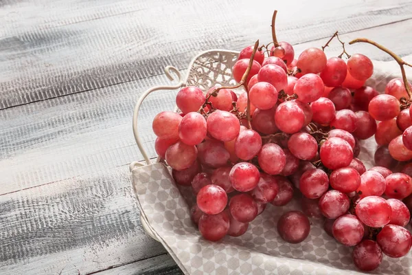 Dienblad met rode druiven op houten tafel, close-up — Stockfoto
