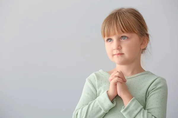 Little girl praying on light background — Stock Photo, Image