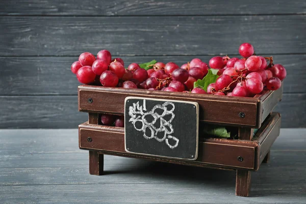 Wooden box with red grapes on table — Stock Photo, Image