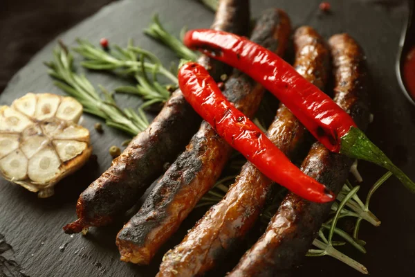 Delicious grilled sausages with vegetables and rosemary on slate plate, closeup — Stock Photo, Image