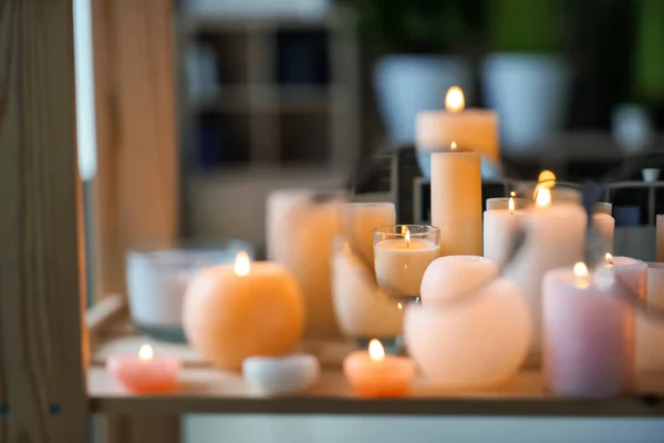 View at beautiful burning candles on wooden table through glasses — Stock Photo, Image