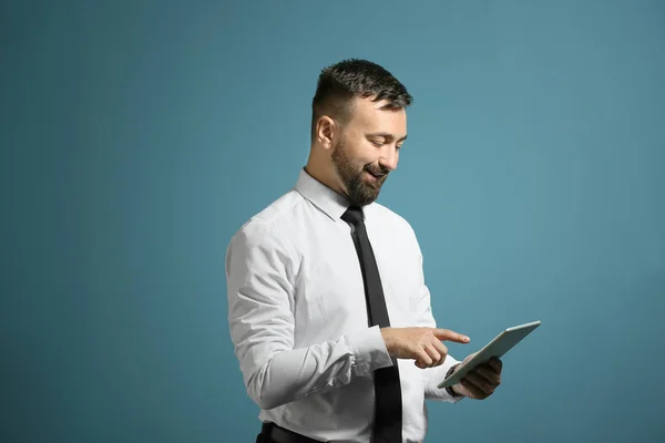 Portrait of handsome businessman holding tablet computer on color background — Stock Photo, Image