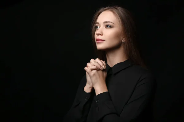 Beautiful young woman praying on dark background — Stock Photo, Image