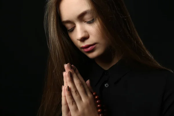 Piękna młoda kobieta, modląc się na ciemnym tle — Zdjęcie stockowe