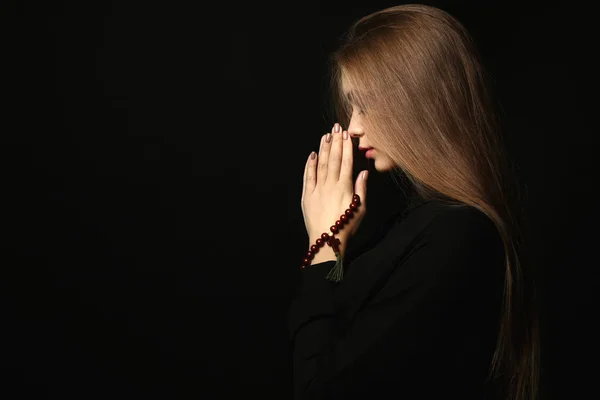 Hermosa joven rezando sobre fondo oscuro — Foto de Stock