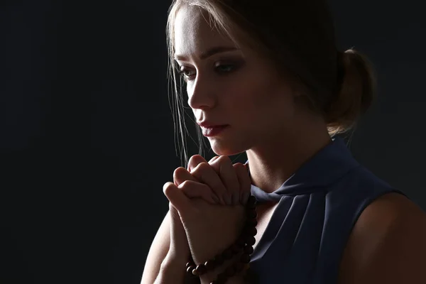 Beautiful young woman praying on dark background — Stock Photo, Image