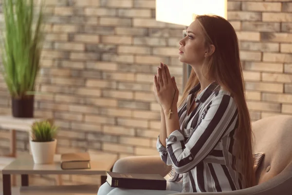 Beautiful young woman praying at home — Stock Photo, Image