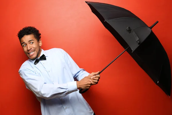 Retrato de homem afro-americano assustado com guarda-chuva sobre fundo de cor — Fotografia de Stock