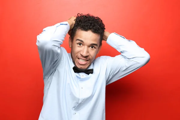 Portrait of stressed African-American man on color background — Stock Photo, Image