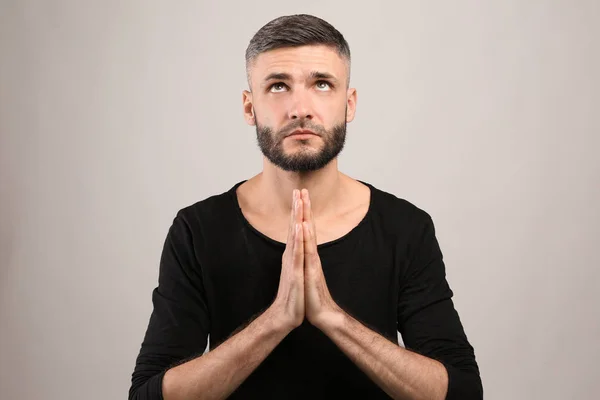 Handsome man praying on grey background — Stock Photo, Image