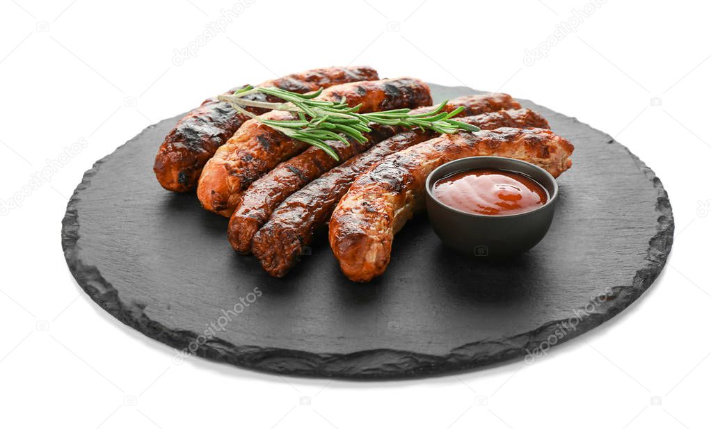 Slate plate with delicious grilled sausages and sauce on white background