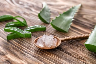 Kaşığı soyulmuş aloe vera ve ahşap masa üzerinde yeşil yaprakları ile