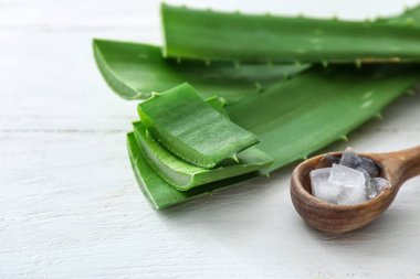 Kaşığı soyulmuş aloe vera ve beyaz masada yeşil yaprakları ile
