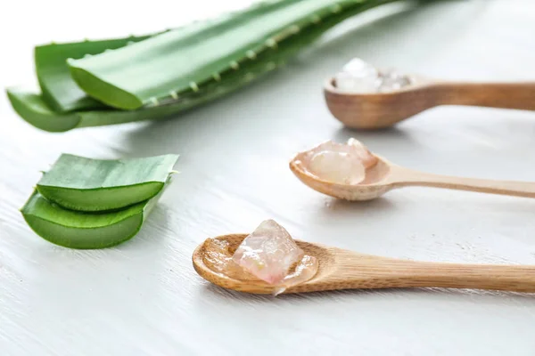 Spoons with peeled aloe vera and green leaves on white table — Stock Photo, Image