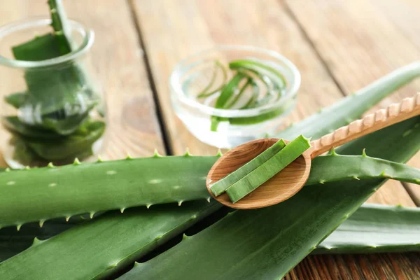 Fresh aloe vera leaves with spoon on wooden table, closeup — Stock Photo, Image
