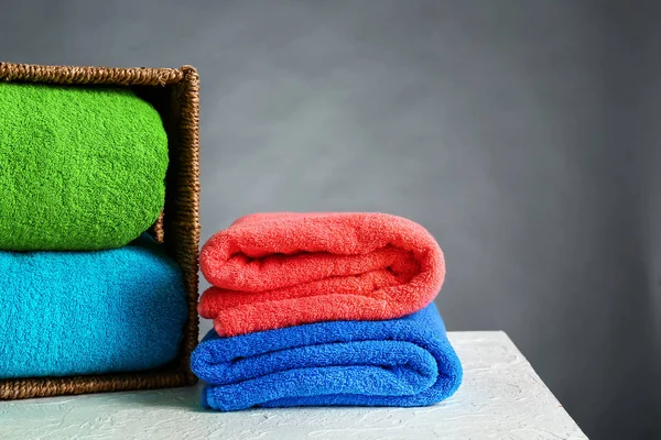 Cesta de vime com toalhas de cor na mesa — Fotografia de Stock