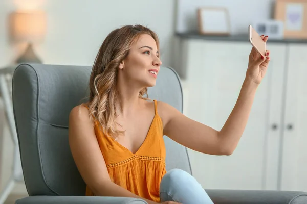 Retrato de bela jovem mulher tomando selfie em casa — Fotografia de Stock