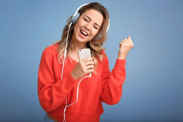 Portrait of beautiful young woman listening to music on color background — Stock Photo, Image