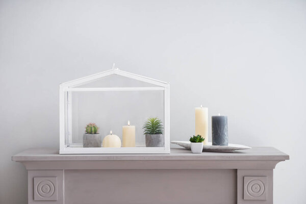 Beautiful burning candles with plants on light table